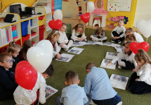 Dzieci oglądają ilustracje przedstawiające sposoby świętowania Dnia Niepodległości